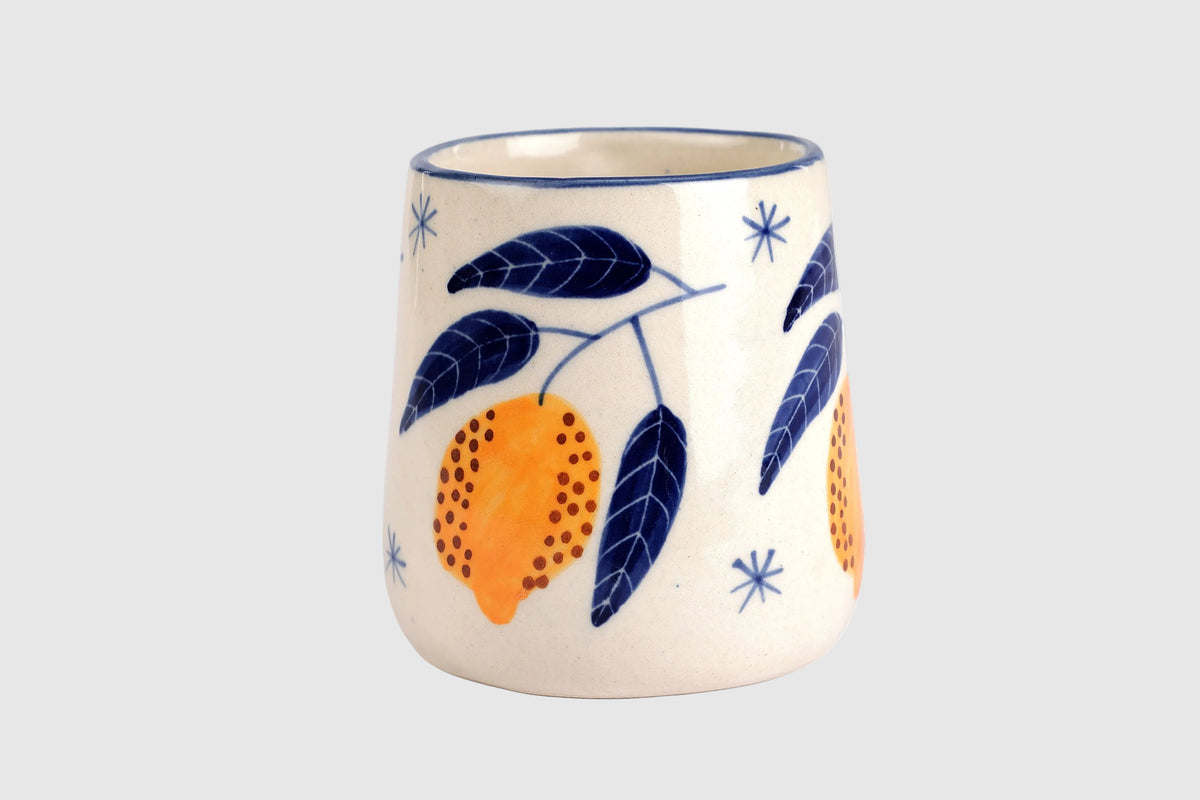 Ceramic mug with orange and leaf design on a white background