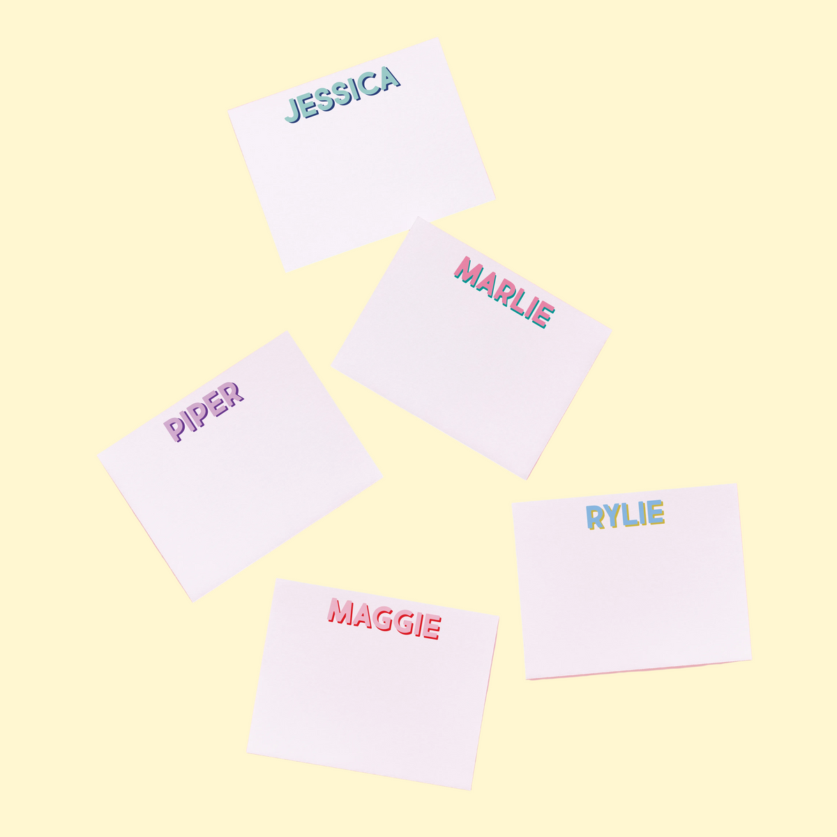 White notecards with names printed in colorful letters on a pink background