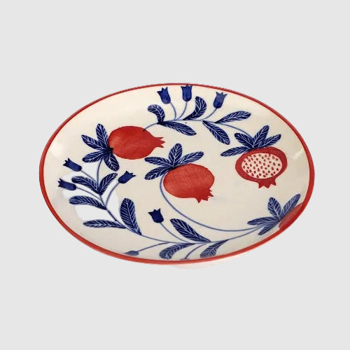 Decorative plate with red pomegranate and blue floral patterns on a white background