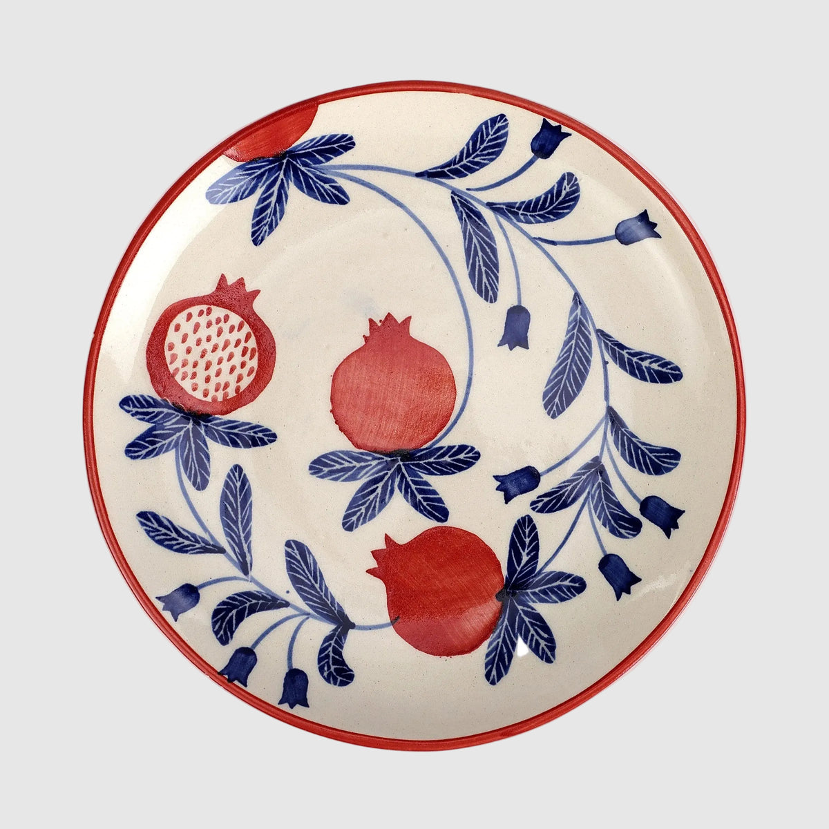 Decorative plate with red pomegranate and blue floral patterns on a white background