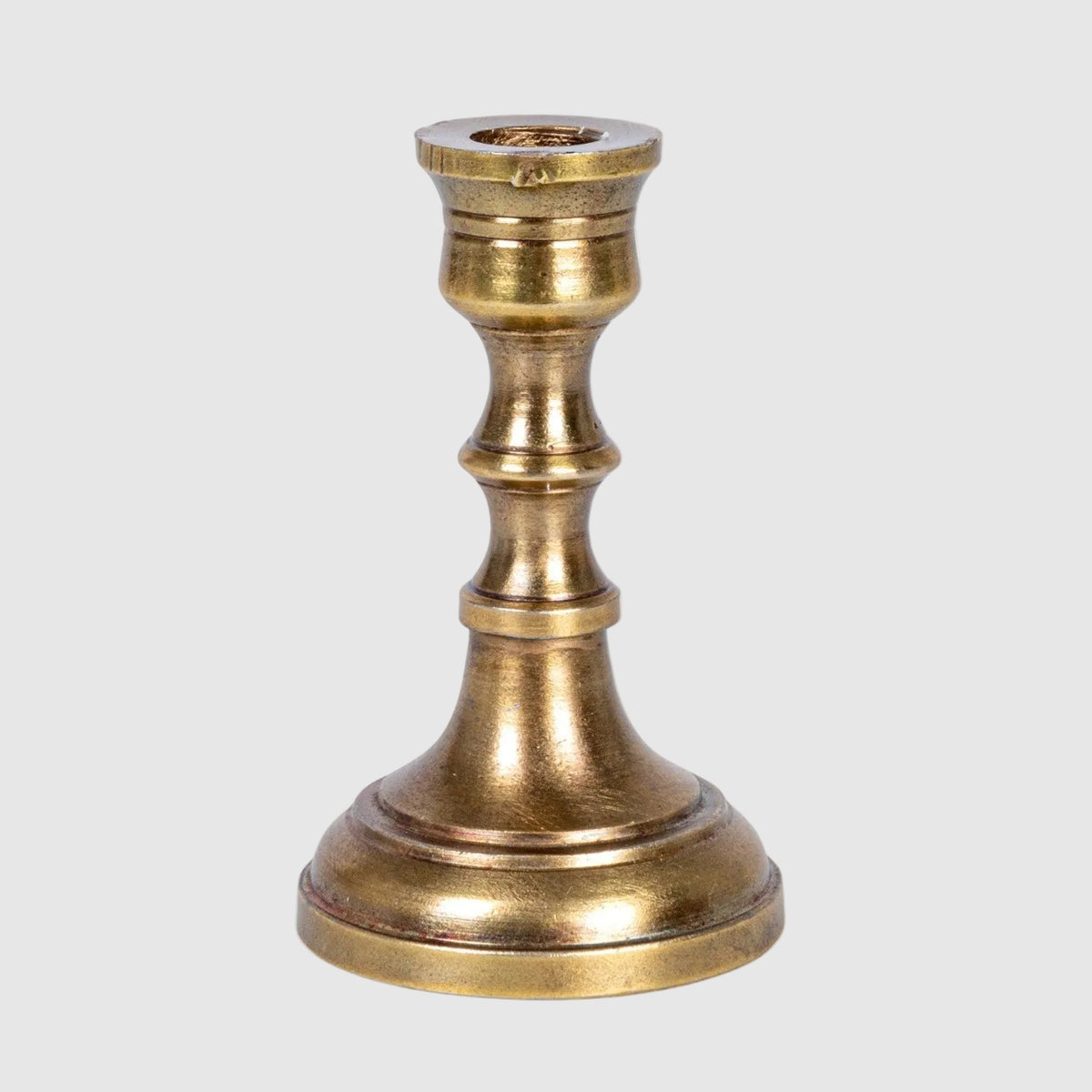 A single brass candlestick holder with a classic tiered design and a central socket, shown on a plain white background.