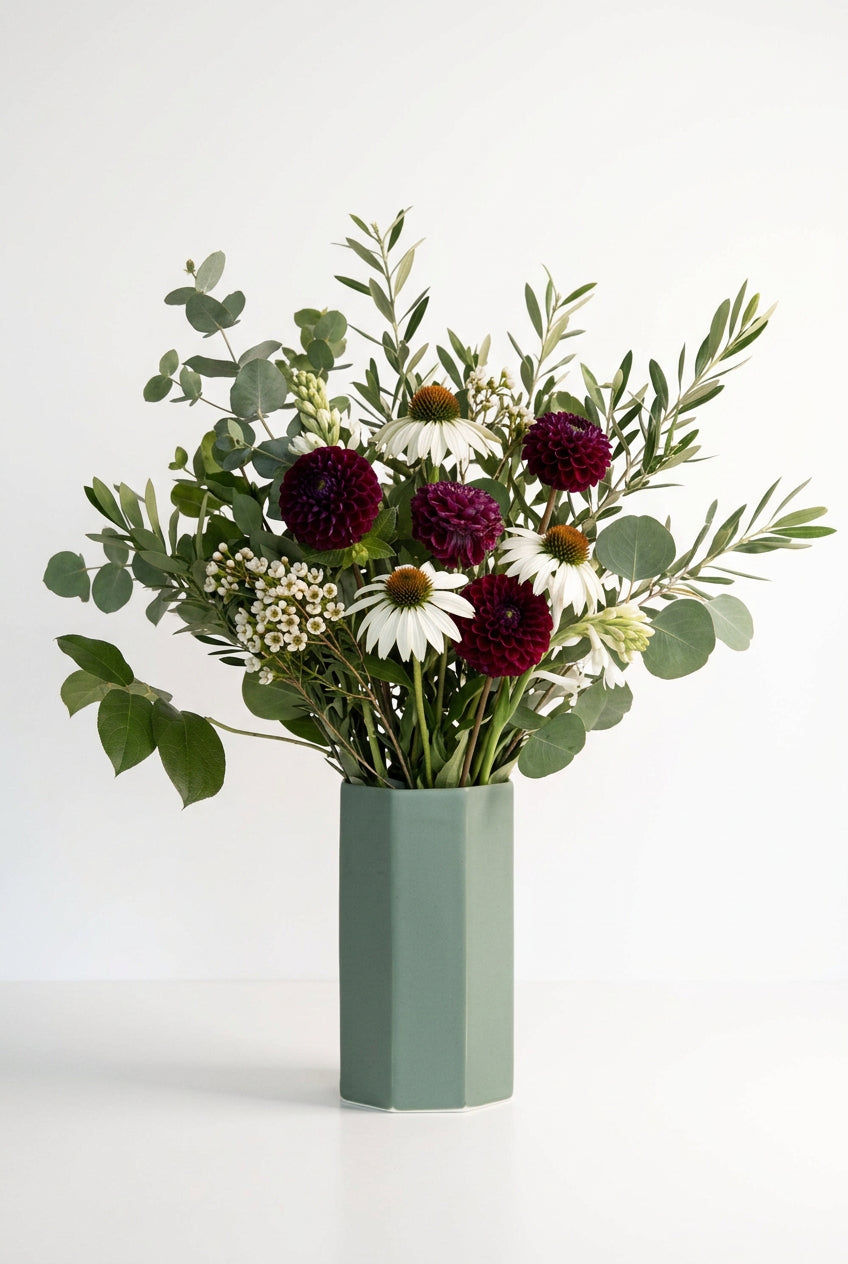 Green vase with purple flowers on a white background