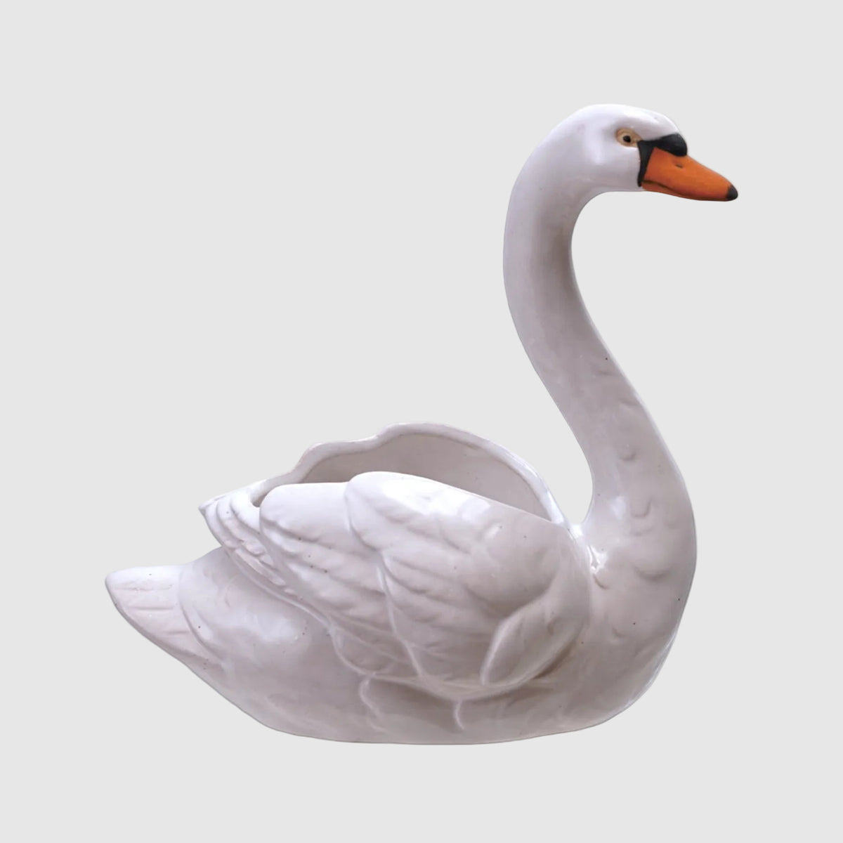 A white ceramic swan-shaped container with a hollow neck opening, featuring a detailed textured body, a white body, and a contrasting orange beak with a small black tip.